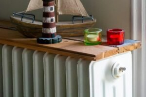 Hand mit Entlüftungsschlüssel am Ventil eines Heizkörpers