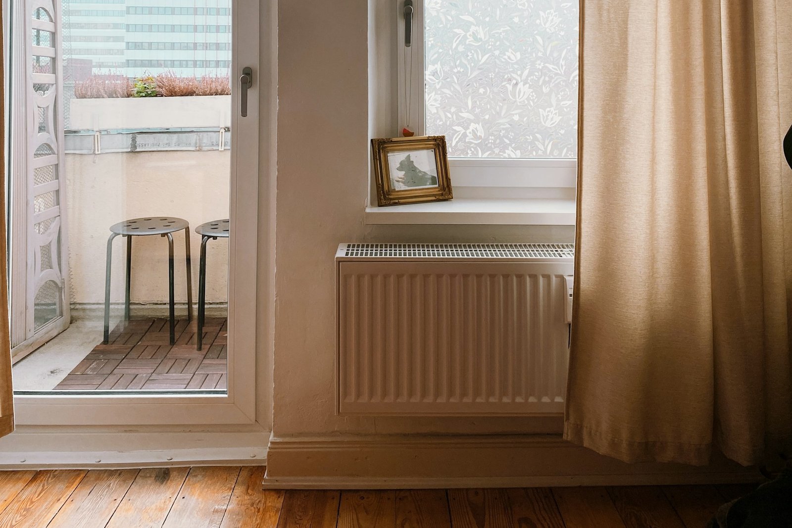 Weißer Heizkörper mit angeschlossenen Heizungsrohren an der Wand