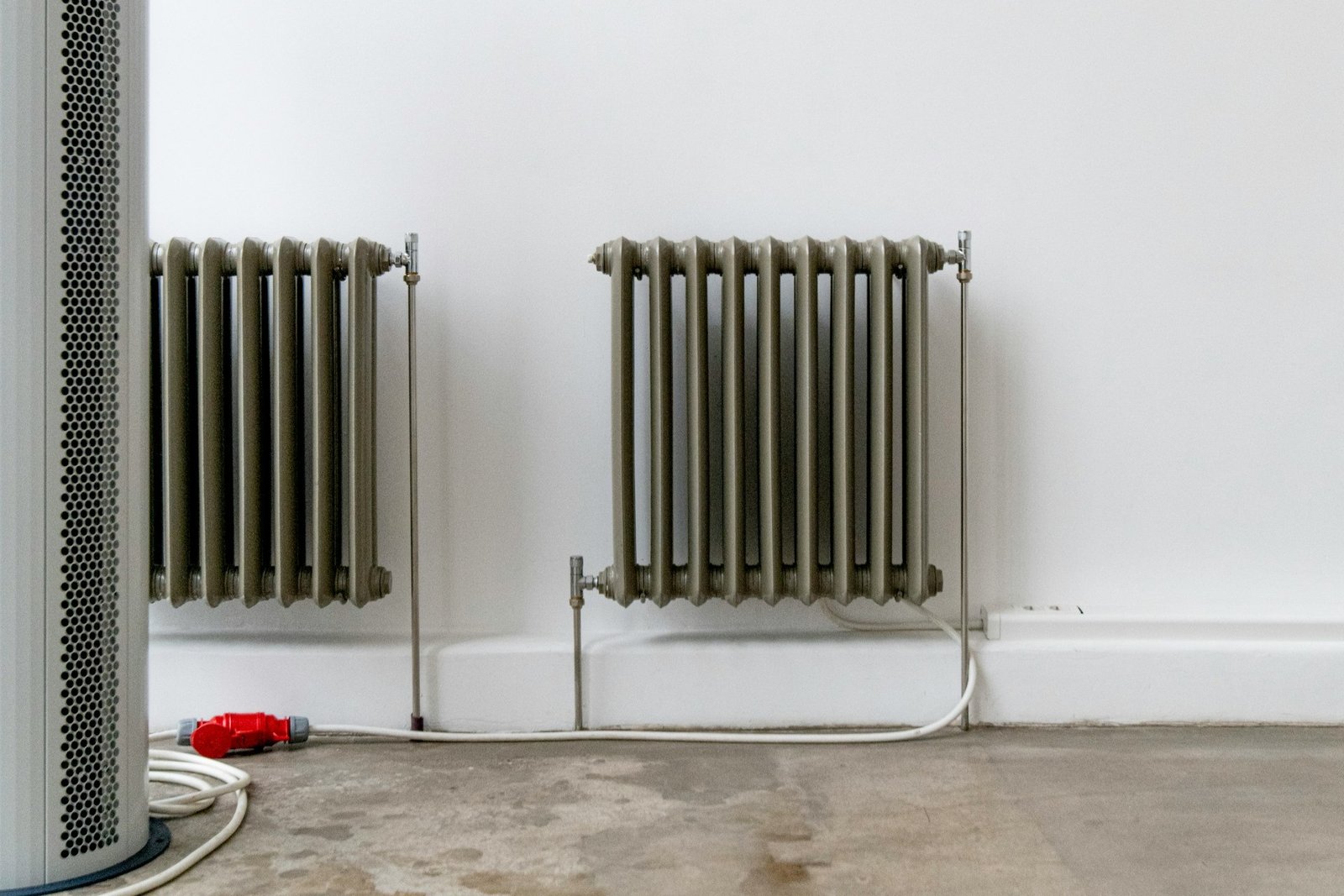 Heizungsrohre verlaufen in einer Wandöffnung neben einem Heizkörper